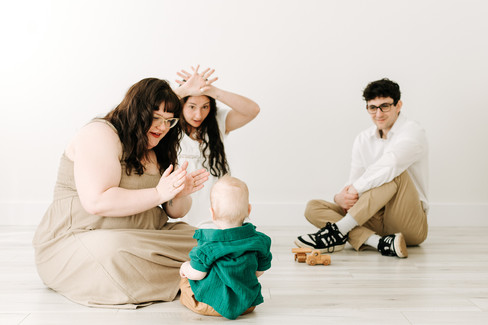 Milestone session in Guelph, Ontario featuring mother, brother, sister, and baby boy playing together in a bright studio setting.