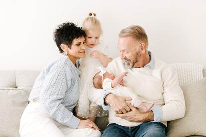 Grandparents with toddler and newborn baby during a newborn session in Guelph, Ontario in a soft studio portrait