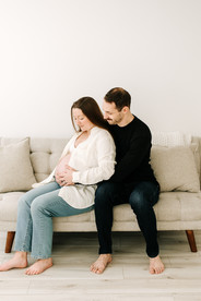Expecting couple holding hands and smiling in a maternity session at Elle Chic Photography Studio, Guelph