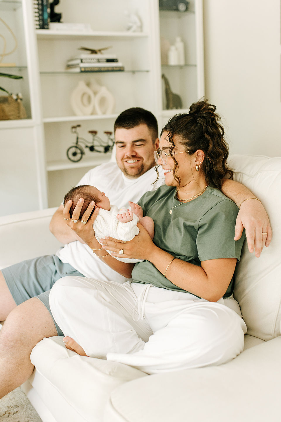 Newborn family session in Guelph, Ontario capturing parents sharing a tender moment while holding their baby at home