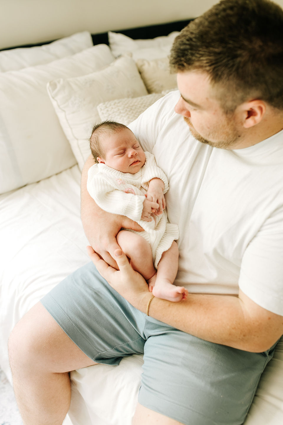 In-home newborn photography in Guelph, Ontario featuring father holding his newborn baby during a quiet moment at home