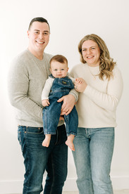 Parents and baby boy together in a first birthday family photoshoot at a photography studio.