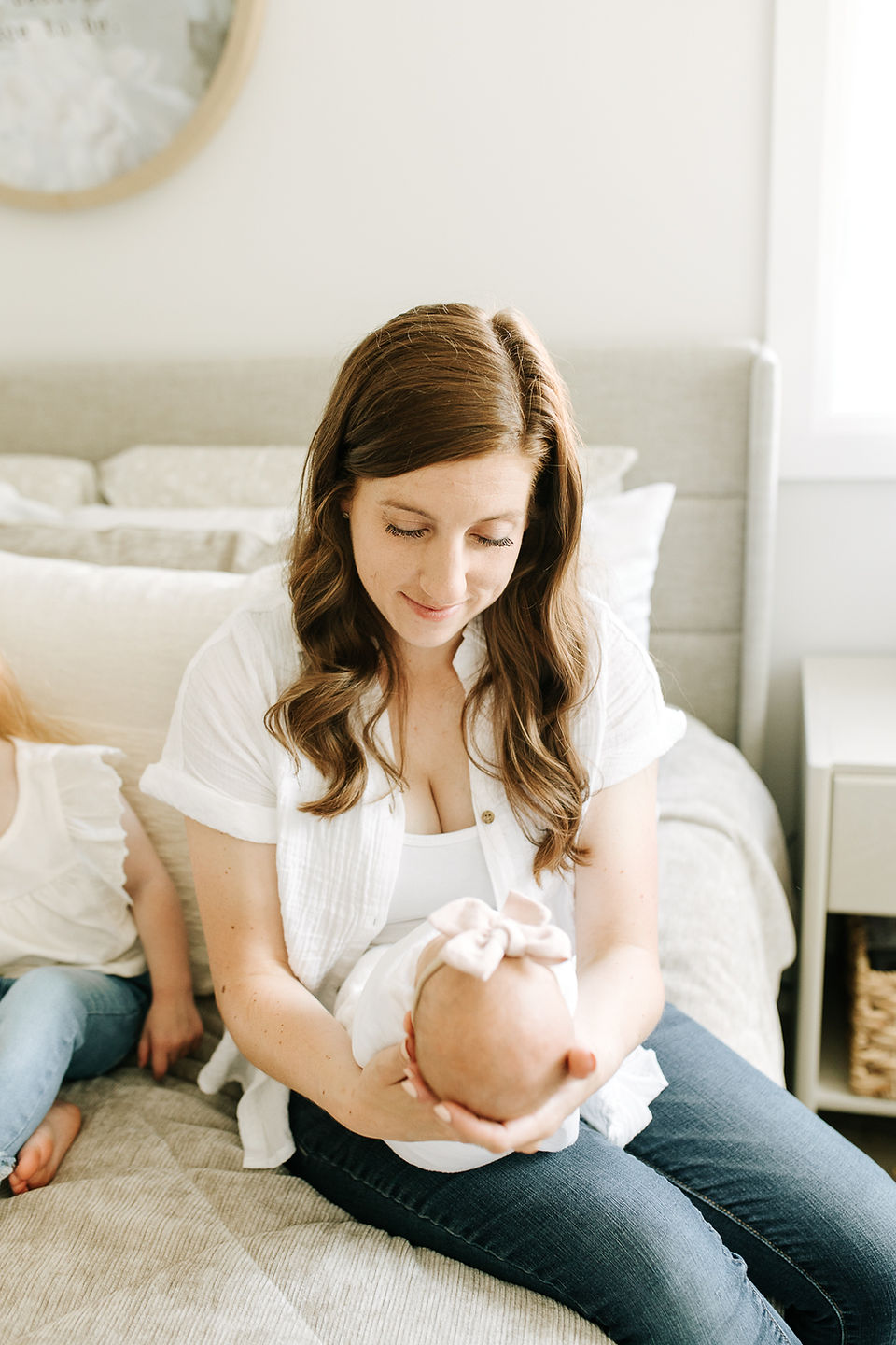 In-home newborn family photography in Guelph, Ontario capturing a mother cuddling her newborn baby in soft natural bedroom light.