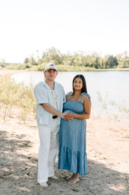 Expecting parents during a beach maternity session in Guelph, Ontario standing barefoot on the shoreline with soft natural light