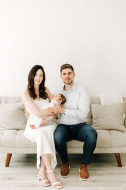 Mom and dad with newborn baby during newborn session in Guelph, Ontario captured in a minimal studio setting with soft lighting