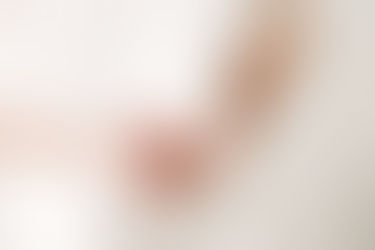 Close-up detail during newborn session in Guelph, Ontario showing parents gently holding newborn baby feet in a bright, minimal studio