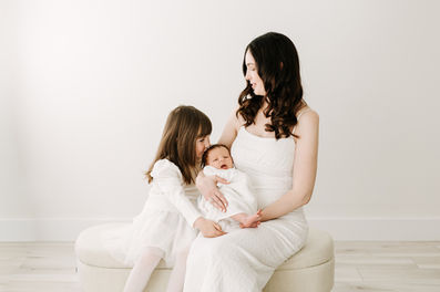 Newborn session in Guelph, Ontario capturing mother with newborn baby and young daughter in a clean, neutral studio setting