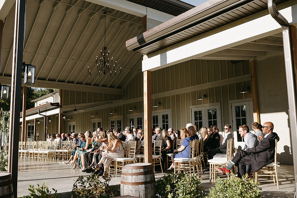 Outdoor covered porch at Hazelnut Farm Events with seated wedding guests under high ceilings and chandeliers.