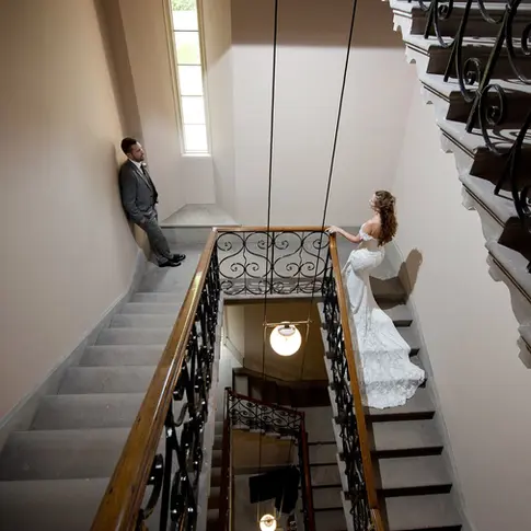 A portrait of the wedding couple on the grand stone staircase inside Hampton Court Castle, highlighting the scale of the interior.