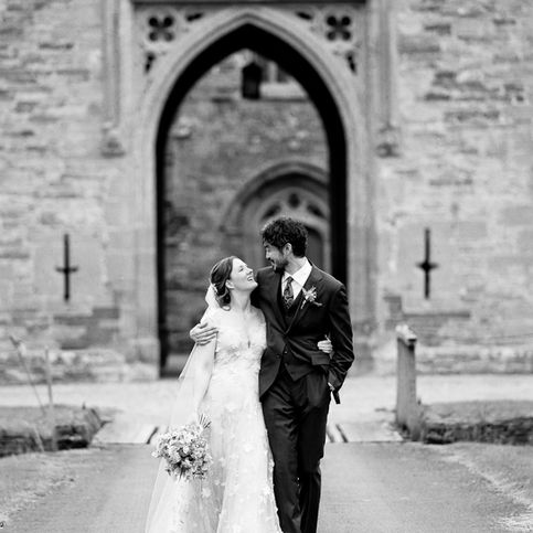 Black and white photograph of bride and groom in front of Hampton Court Castle exterior taken on a wedding day.
