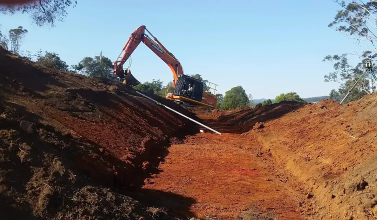 Master earthworks operator Doc Spice cutting in a back-flood swale spillway with an excavator on a regenerative farm project