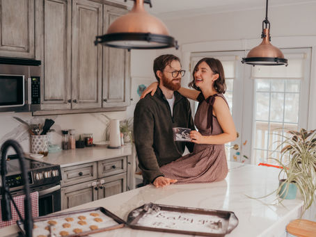 Couple announcing pregnancy in their kitchen laughing on the counter