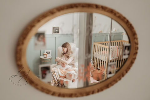 A heartfelt mirror reflection of a mom nursing her baby while surrounded by soft, calming decor that exudes warmth and tenderness