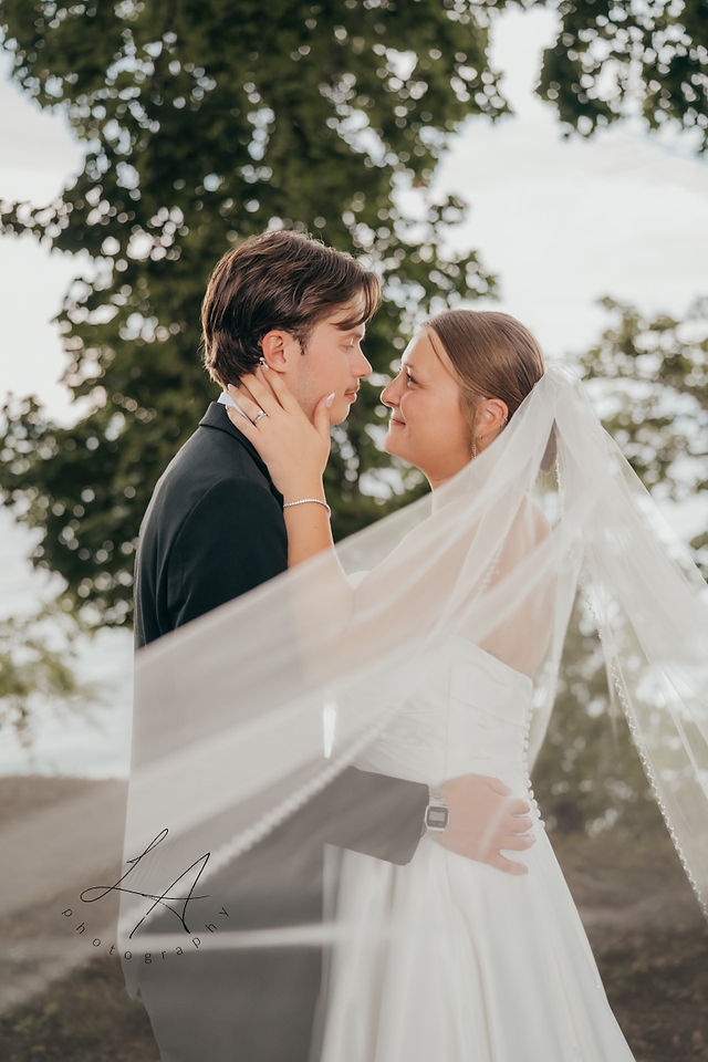 Wedding bride and groom looking at each other with veil blowing in the breeze