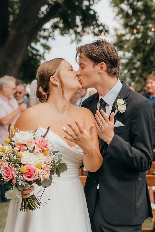 Wedding couple, bride and groom kissing showing off rings