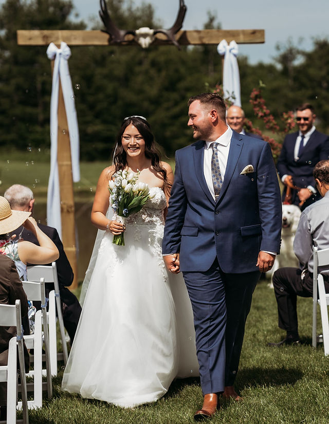 Bride and groom walk down aisle at backyard wedding ceremony