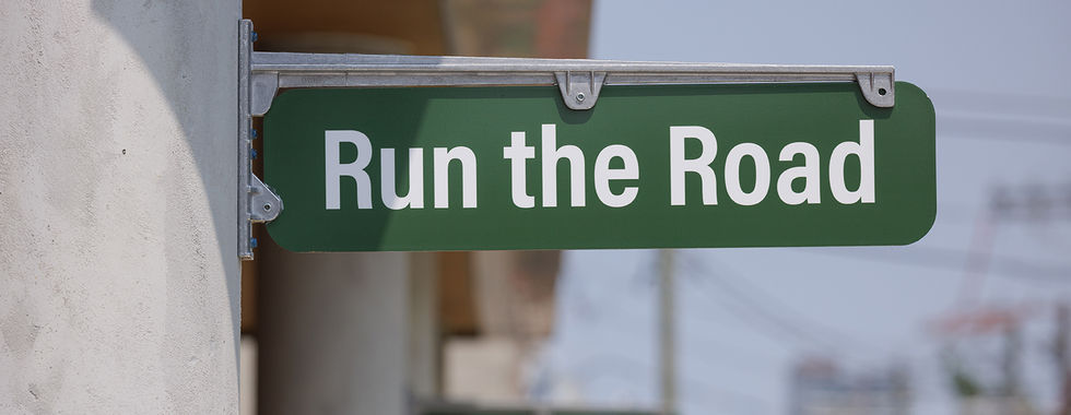 "Run the Road" green street sign