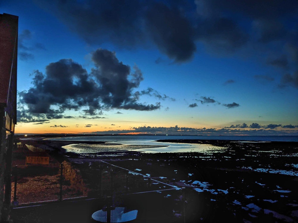 Sunset, orange and deep blue sky, clouds, sea and bank top cottage, cresswell beach, Druridge bay, Northumberland.