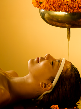 Woman receiving Shirodhara, a stream of warm oil poured onto the forehead