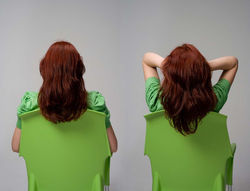 Rear view of two identical redheads on green chairs, the right one with hands in her hair.