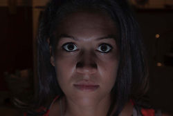 Face 8. Horizontal color close-up of a man looking directly at the camera, with low-key indoor night