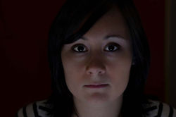 Face 4. Horizontal color close-up of a man looking directly at the camera, with low-key indoor night