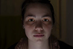 Face 3. Horizontal color close-up of a man looking directly at the camera, with low-key indoor night