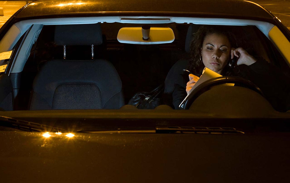 A young woman on the phone, sitting in a car, at night.