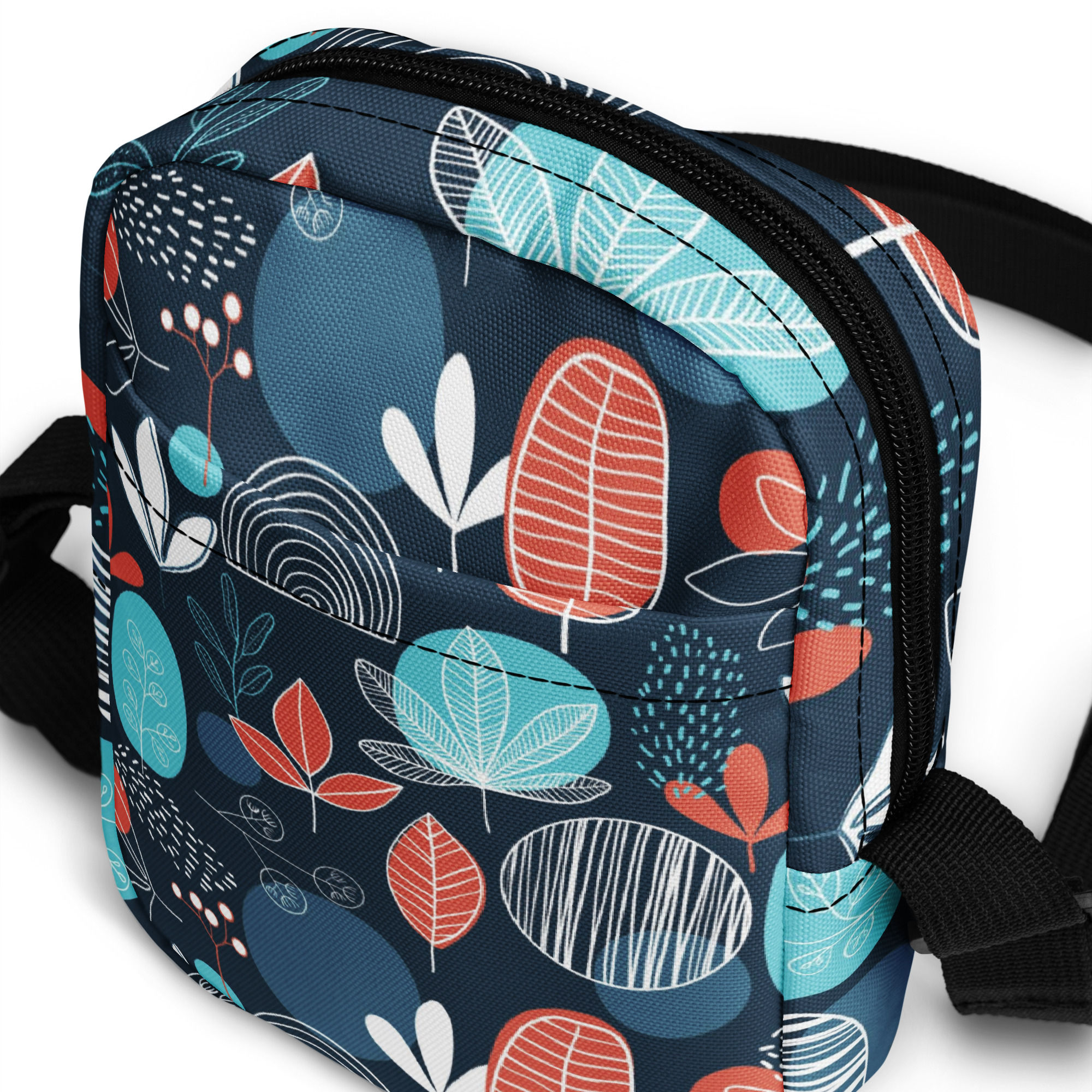 Midnight blue crossbody sling bag featuring a vibrant red and teal abstract leaf pattern with an adjustable black strap.