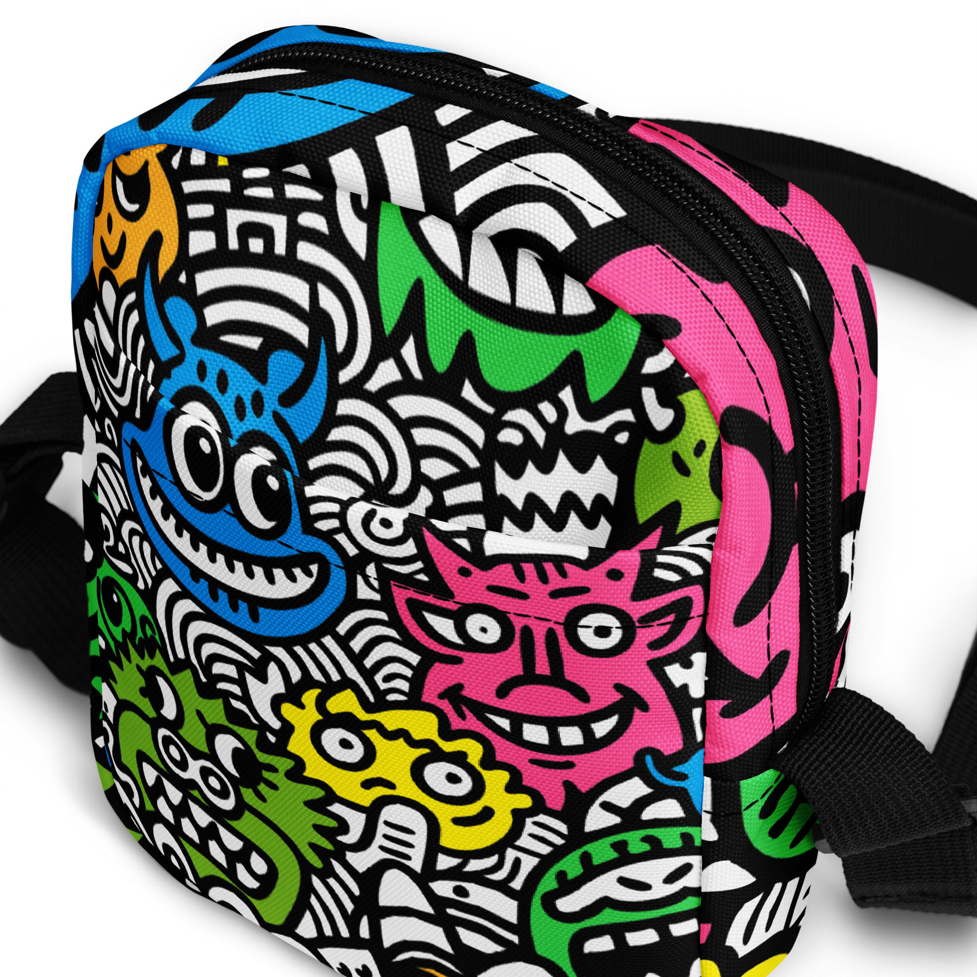 A crossbody sling bag featuring a vibrant, colourful doodle pattern of animated monsters in neon pink, green, blue, yellow.