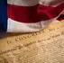 American flag draped over the Declaration of Independence document dated July 4, 1776. The flag's colors are vivid red, white, and blue.
