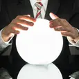 Man in a suit holds a glowing white crystal ball over a glossy black surface, creating a mysterious mood.