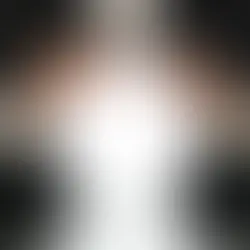Man in a suit holds a glowing white crystal ball over a glossy black surface, creating a mysterious mood.