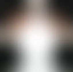 Man in a suit holds a glowing white crystal ball over a glossy black surface, creating a mysterious mood.