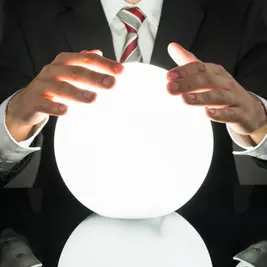 Man in a suit holds a glowing white crystal ball over a glossy black surface, creating a mysterious mood.