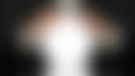 Man in a suit holds a glowing white crystal ball over a glossy black surface, creating a mysterious mood.