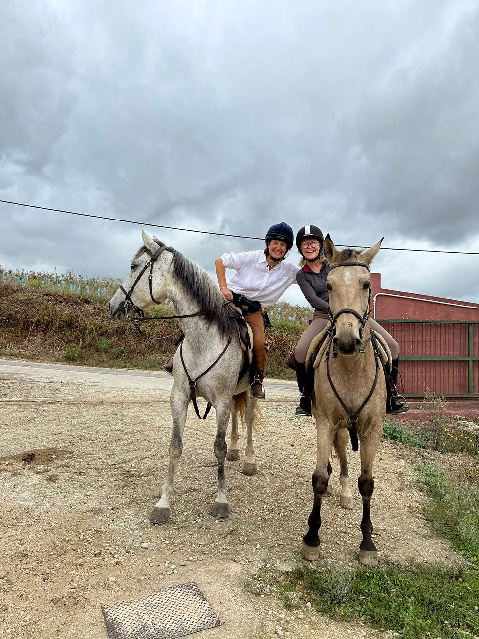 Two happy female riders leaning towards each other for a pose in the saddle.