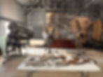 Three dinosaur skulls and fossil bones on a table inside a warehouse