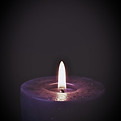 Bougie violette allumée sur fond noir, symbolisant la transformation et l'éveil spirituel.