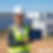 A high-quality, photorealistic image of a young female electrical engineer wearing a white hard hat and high-vis safety vest, standing confidently in front of a massive utility-scale solar farm and modern battery energy storage system (BESS) units. She is holding a digital tablet displaying complex single-line diagrams. The lighting is bright and sunny, conveying clean renewable energy and professional compliance. Shot with a 50mm lens, shallow depth of field, corporate professional photography style. add website www.eservices4u.com.au in the below right down in a professional way