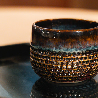 Close up of carved openings in a handmade ceramic candleholder.