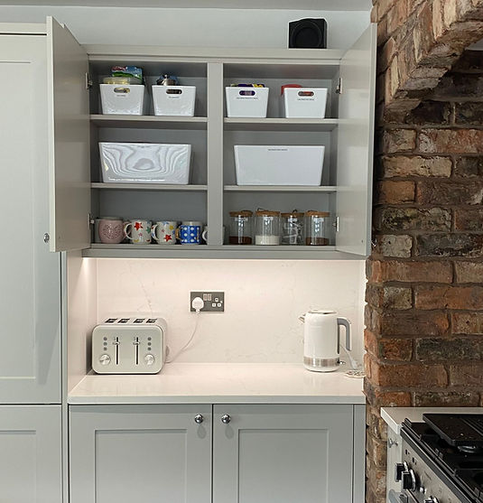 Beautifully organised modern kitchen cupboard with open doors containing containers and decanted tea and coffee. Toaster and kettle on the side.