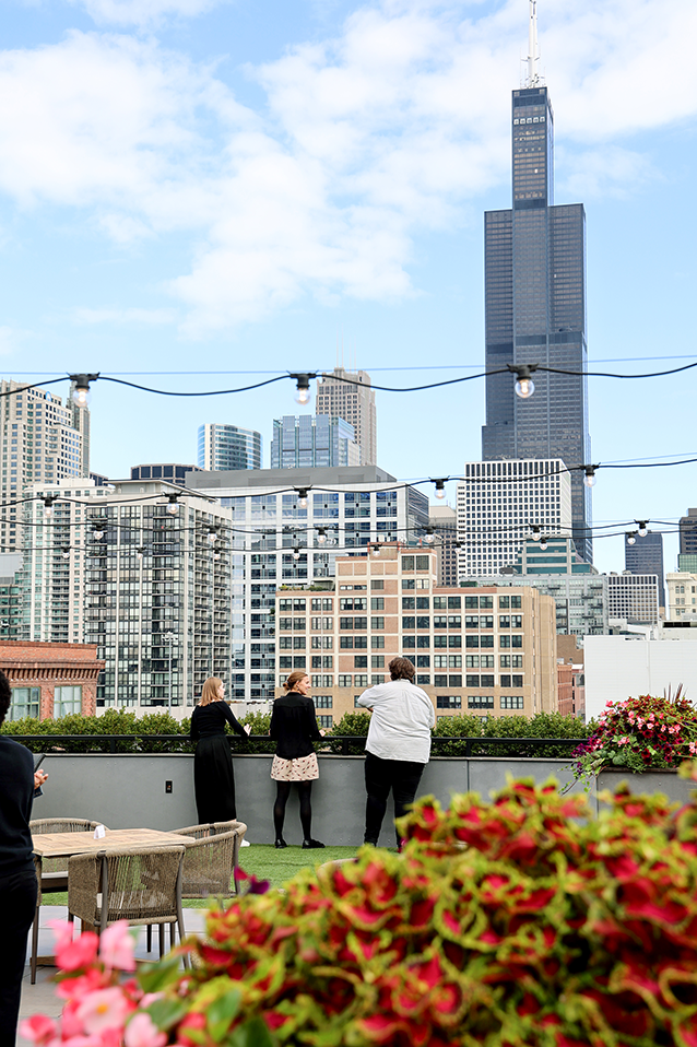 Design B&B employees standing at a penthouse overlooking the Chicago skyline with flowers in the foreground.