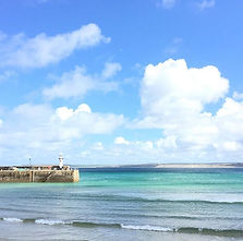 St Ives harbour on a sunny day with Smeaton's pier on the foreground looking out towards St Ives Bay and Gwithian beyond