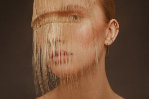 avant-garde blonde hair styling with artistic fringe, soft glow and clean skin texture.
