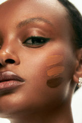Beauty image of an African model wearing three skin tone foundations on her cheek.