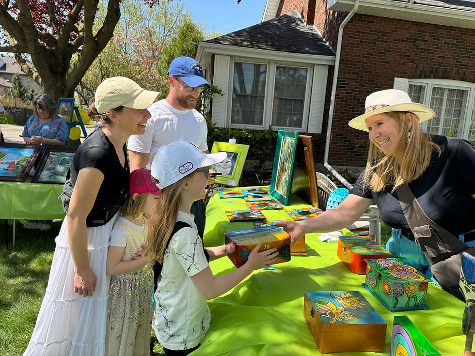 During the 2025 Banfield Art Crawl, Maeve Van Wylie and her family - Grace Van Wylie, Marcia Van Wylie and Derek Wylie, purchase a painted box from artist Jennifer Adams who specializes in paintings, painted boxes, paddles and mirrors.