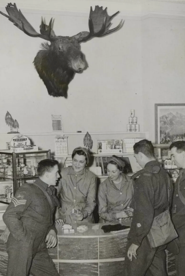 Canadian Armed Forces members gather at London’s Beaver Club, a wartime social hub that offered servicemen and women a taste of home with Canadian sweets, CBC radio broadcasts, and holiday comforts.