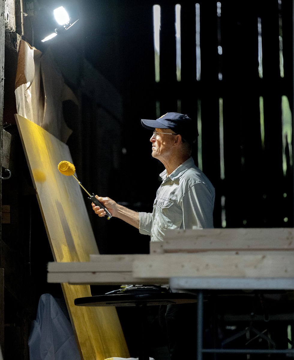 Volunteer Stan Muldoon paints the backdrop for a message board in the barn at Haute Goat Farm.