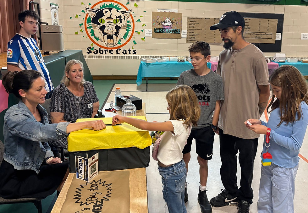 Ms. Goebel and Ms. Zandstra, along with volunteer Brendon Zandstra-Rankin, sell cake raffle tickets to Eleanor, six, Leland, 12, Lila, eight, and their dad, Joey Bettencourt. Diane Danen photo